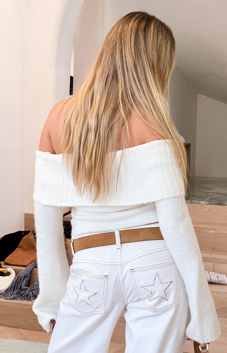 Back view of the cream off-shoulder sweater with a wide folded neckline and soft ribbed knit