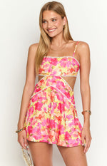Front view of a yellow floral mini dress with white pom-pom trim and waist cutouts