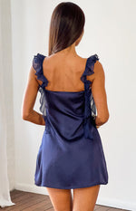 Rear view of a navy satin mini dress with a square back and sheer ruffled shoulder straps