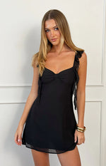 Black chiffon mini dress with a sweetheart neckline, central bow, ruffled shoulder straps, and sheer hem