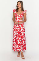 Brunette model wearing a red and white cut out floral maxi dress with brown sandals and a gold necklace and gold bracelet.