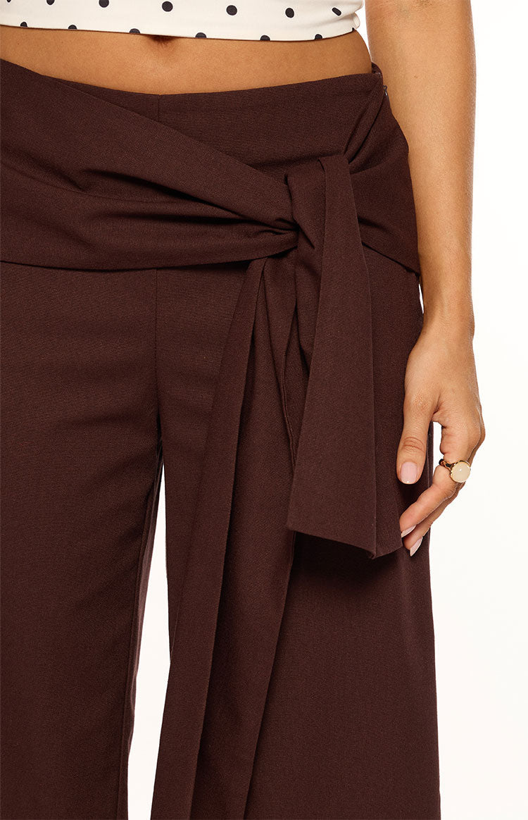 Close-up of the brown pants showing the knotted self-tie waist and draped fabric detail