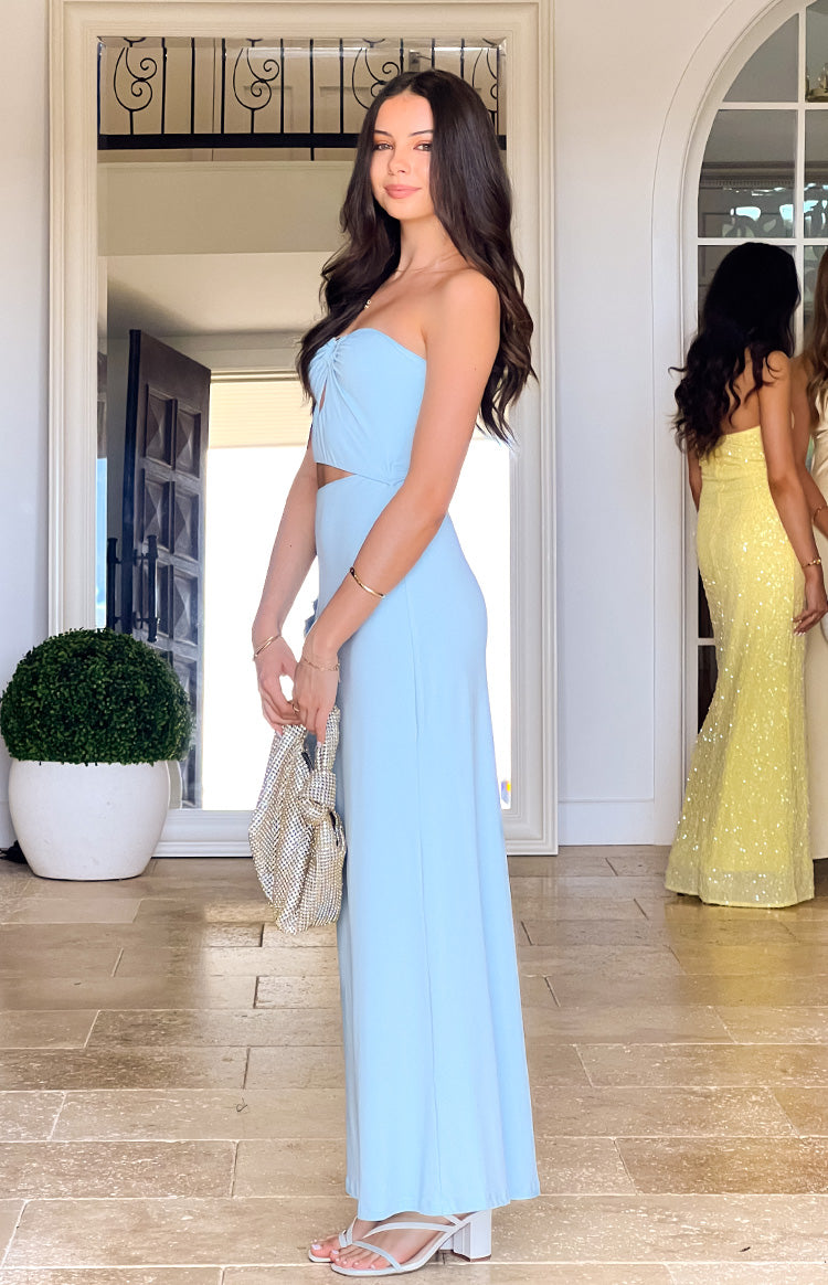 Side view of a light blue strapless maxi dress with a ruched bust and side cutout flowing to the floor