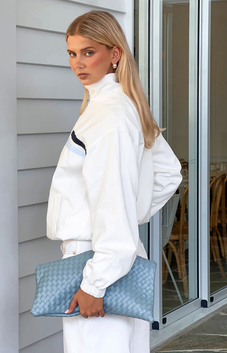 Side view of a cream funnel neck jacket with dark and light blue contrast stripes and elasticated cuffs