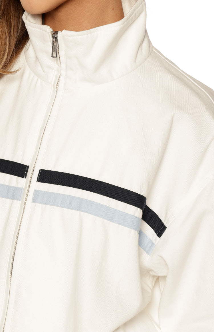 Close-up of the cream funnel neck jacket with a silver zipper and black and light blue chest stripes