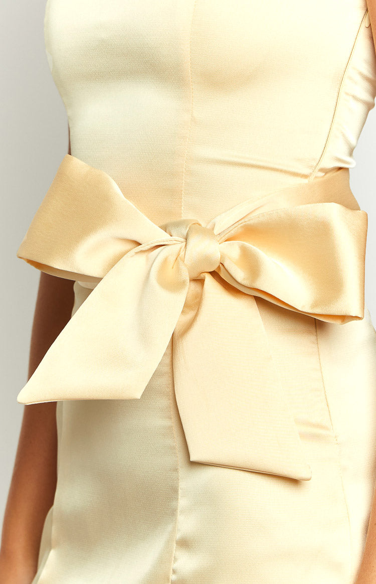 Close-up of the large, structured yellow satin bow detail at the waist of the mini dress
