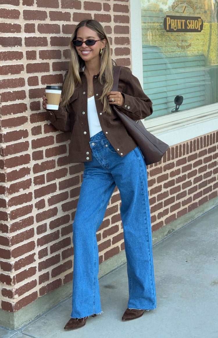 Mid wash blue wide-leg jeans with an uneven crossover waist and frayed hems