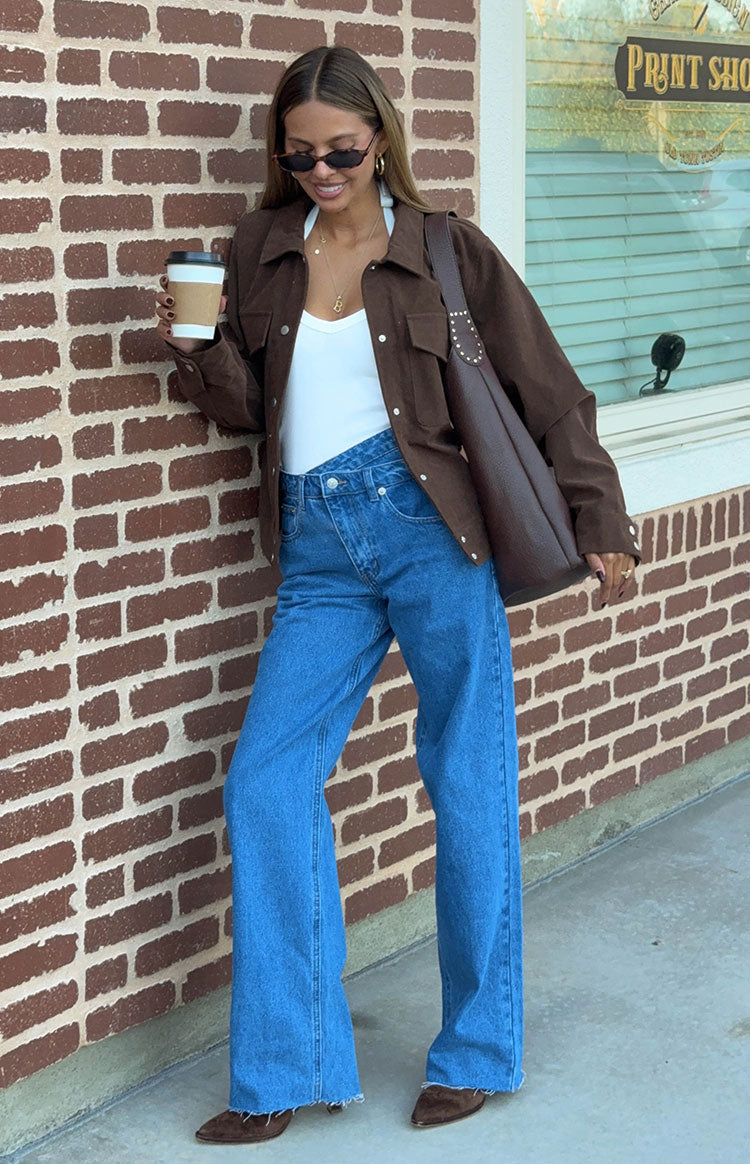 Mid wash wide-leg jeans with an uneven crossover waist and frayed hems