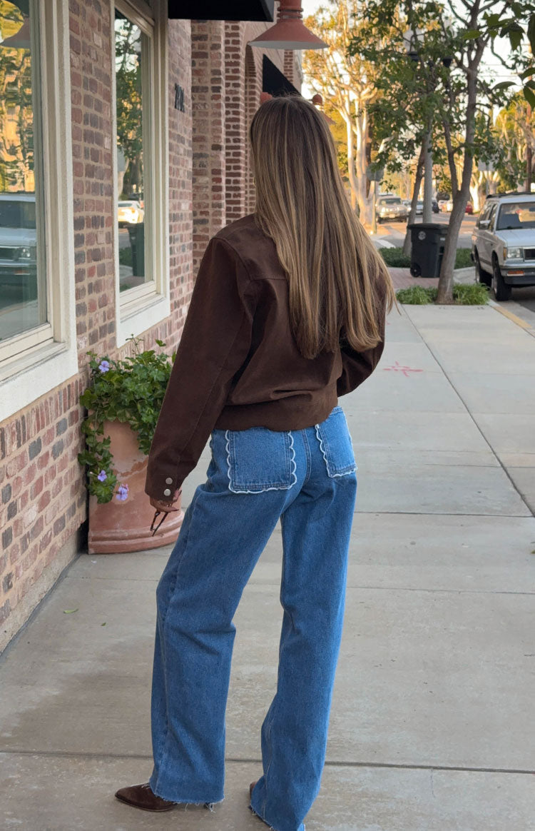Rear view of mid-wash jeans with white scalloped back pockets and wide legs