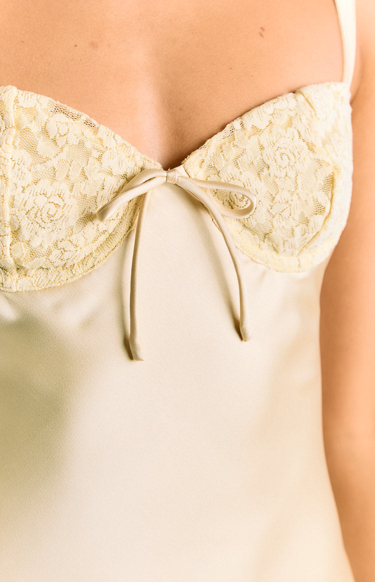 Close-up of the yellow satin mini dress bust with delicate floral lace cups and a small tie detail