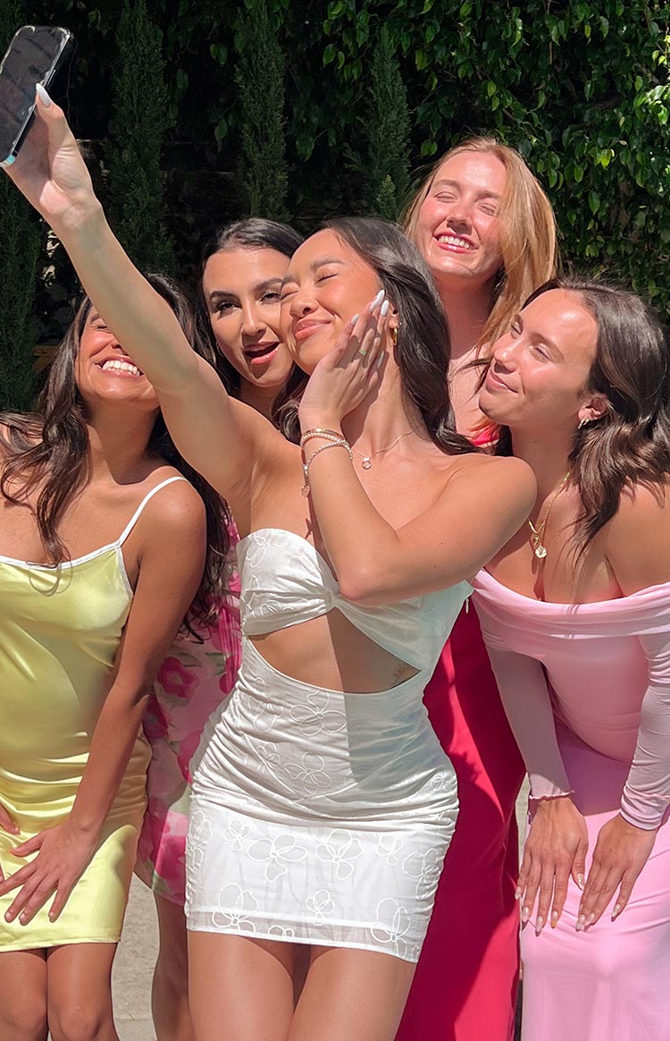 White strapless mini dress with a twisted bust, front cutout, floral embroidery, ruched sides, and mesh hem