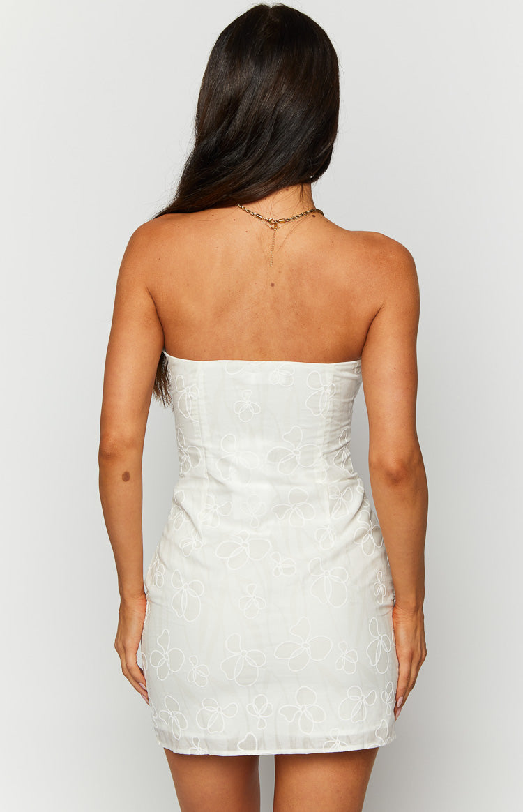 Rear view of a white strapless mini dress with a subtle floral outline pattern and fitted back