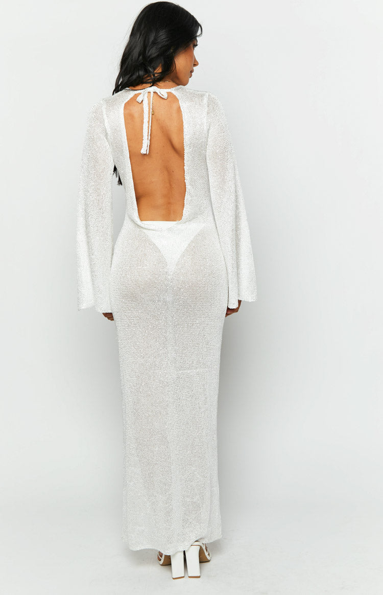 Rear view of a white sequin knit maxi dress with a low open back, tie neck detail, and long bell sleeves