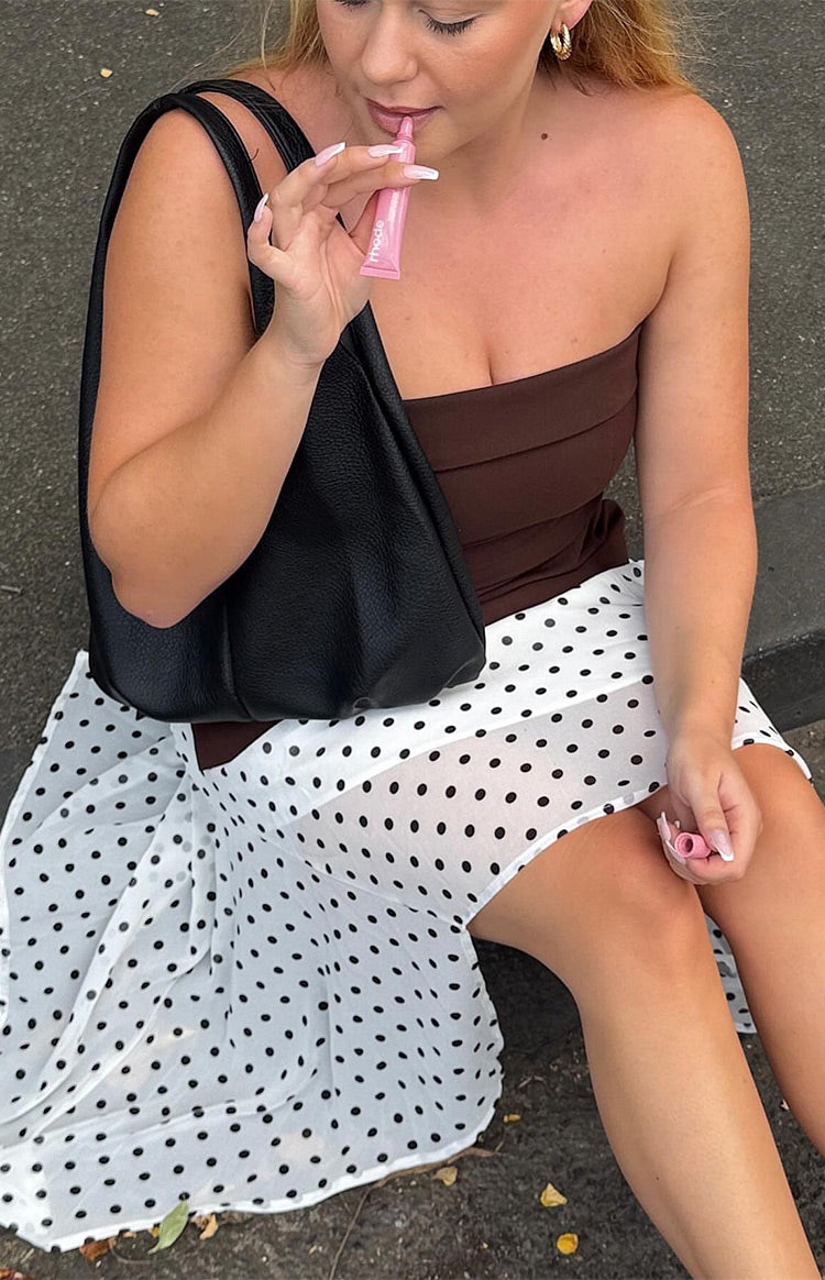 White polka dot hanky hem midi skirt with a flowy drape, seen from a seated angle