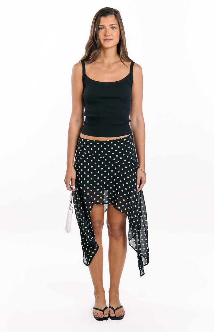 Front view of a black polka dot hanky hem midi skirt with white dots and a flowy silhouette