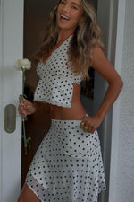 Side view of a white polka dot hanky hem midi skirt with a flowy silhouette