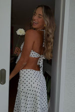 Side view of a white polka dot midi skirt with a flowy hanky hem and subtle side zipper detail