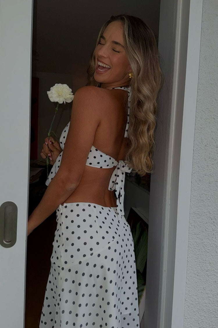 Side view of a white polka dot midi skirt with a flowy hanky hem and subtle side zipper detail