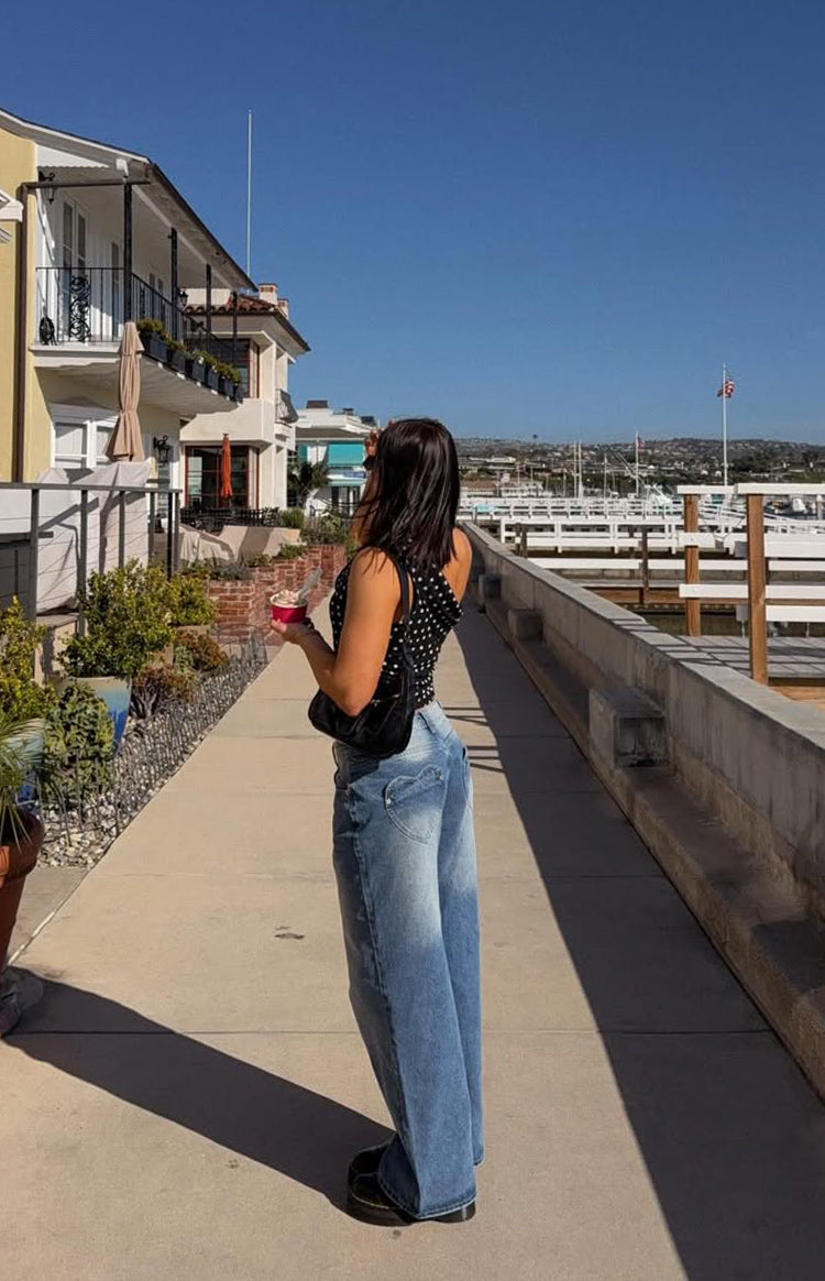 Side view of a black polka dot off-shoulder top with a fitted silhouette