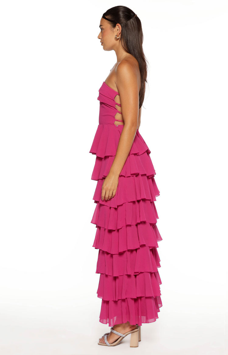 Side view of a fuchsia strapless maxi dress with side cutouts and full tiered ruffles