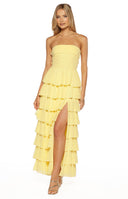 Model wearing a lemon yellow strapless maxi dress with tiered ruffles and a side slit elegant for a Formal event
