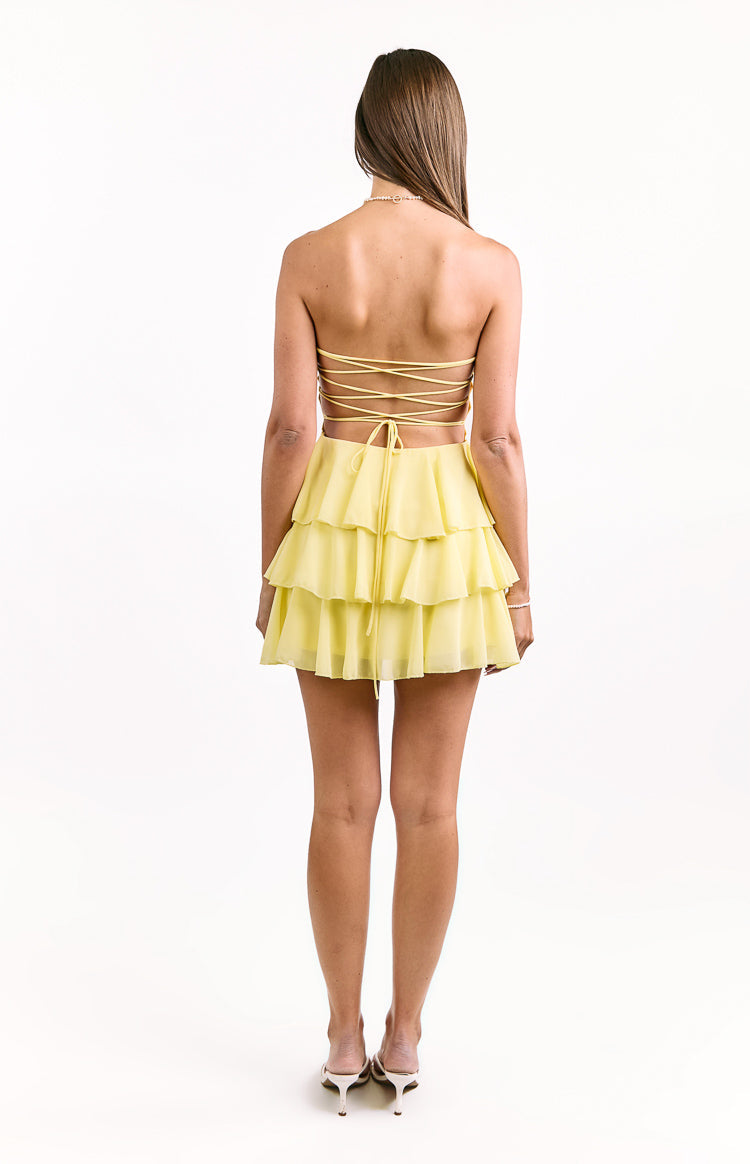 Rear view of a yellow strapless mini dress with a criss-cross lace-up back and tiered ruffle skirt
