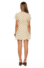 Rear view of a cream polka dot mini dress with short flutter sleeves and a flared hem