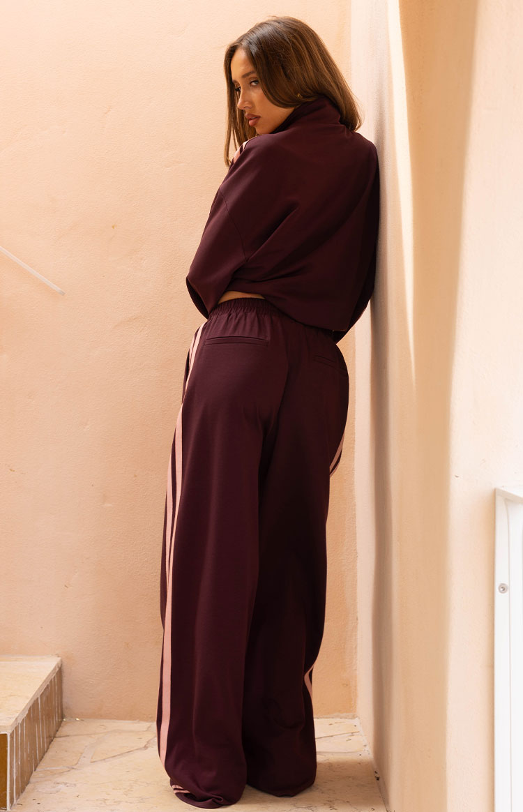 Side view of a cropped burgundy track jacket with a high collar and relaxed long sleeves
