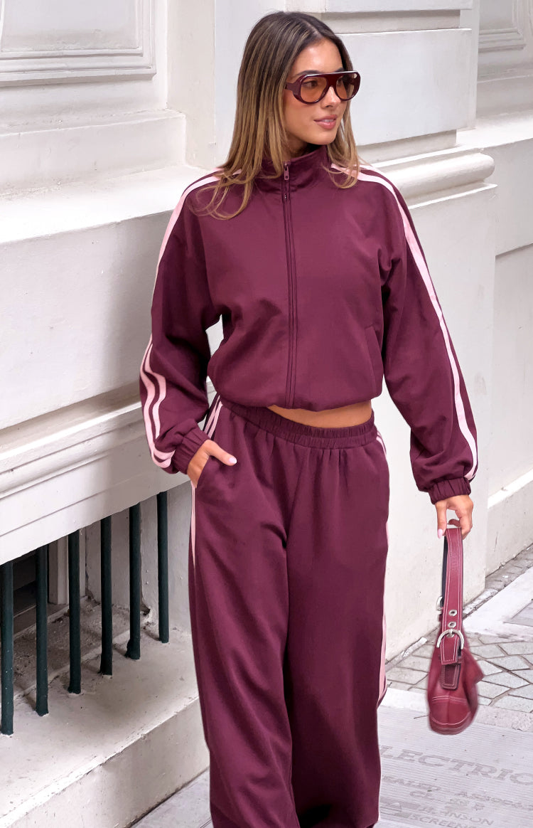 Cropped burgundy track jacket with a high neck, full zip front, and pink stripes down the long sleeves
