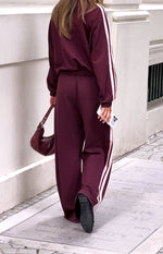 Rear view of burgundy wide-leg track pants with a pink double stripe down each side