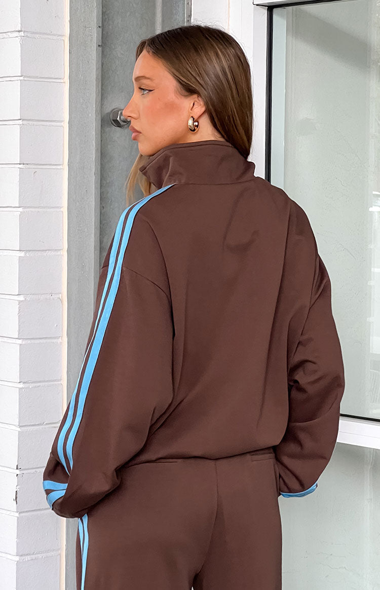 Side view of a chocolate brown jacket featuring a high neck and light blue stripes running down the long sleeves