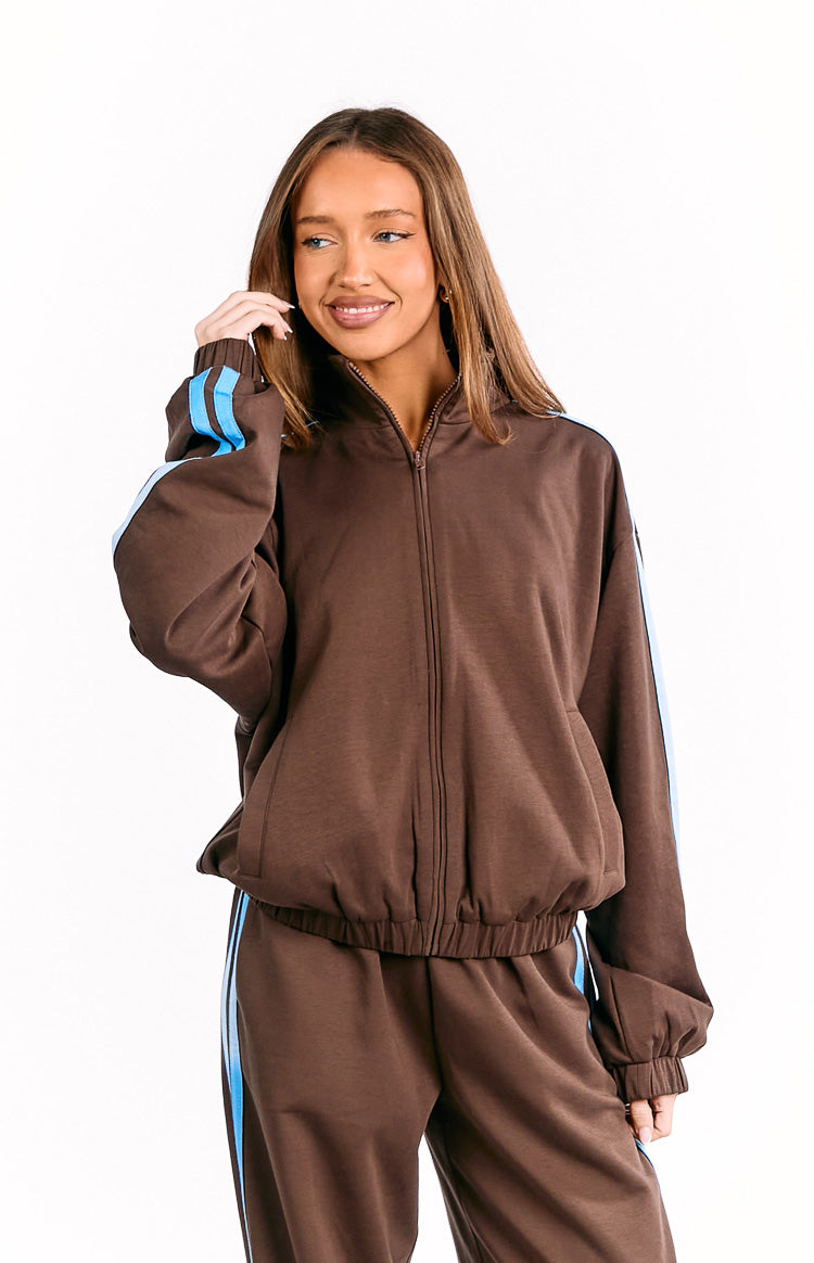 Front view of a chocolate brown zip-front jacket with a stand collar, blue sleeve stripes, and elasticated hem