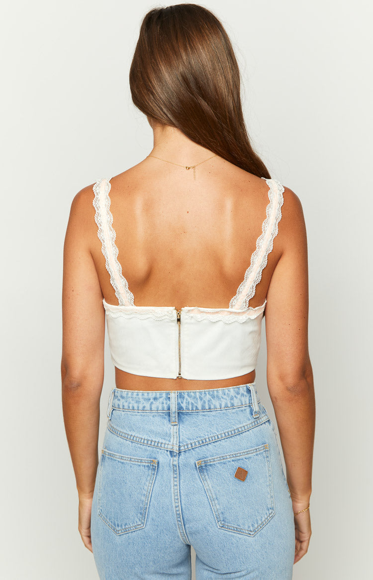 Rear view of a white corset top with lace trim straps and an exposed gold zipper