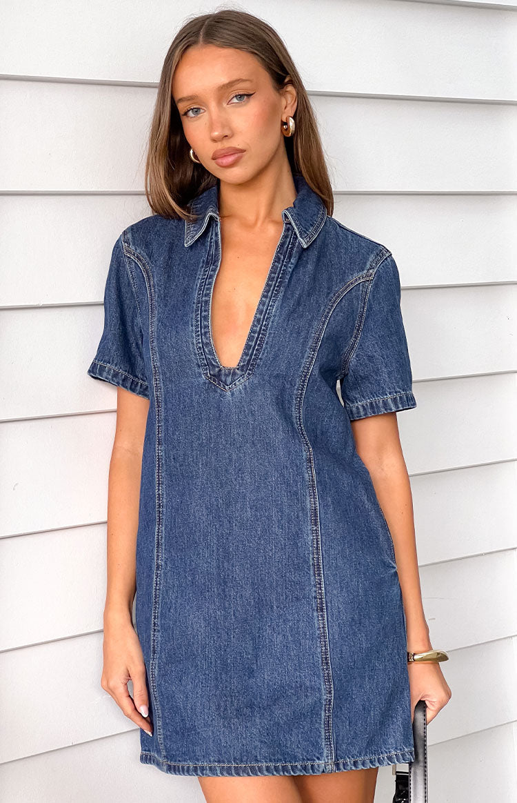 Front view of a dark wash denim mini dress with a collared deep V-neck and short sleeves, showing contrast stitching