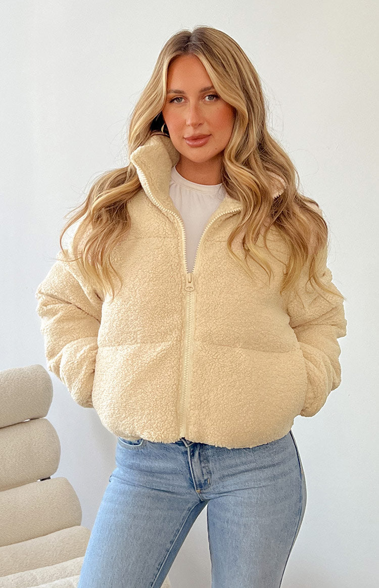 Detail shot of the cream teddy puffer jacket's full-length zipper and plush sherpa fabric