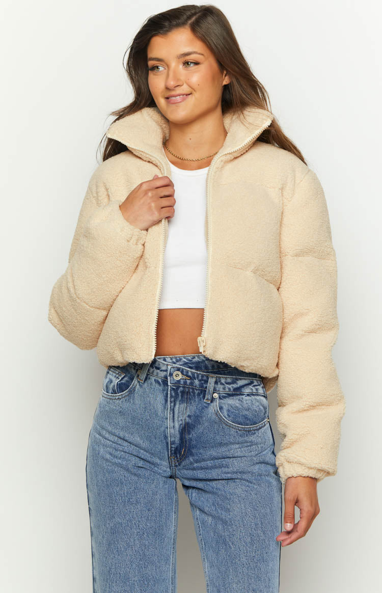 Close-up of the cream teddy puffer jacket's textured fabric, white front zipper, and stand collar