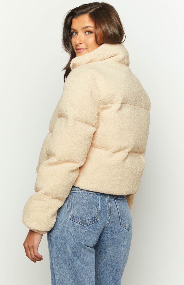 Side view of a cream teddy puffer jacket with a high collar and cropped silhouette