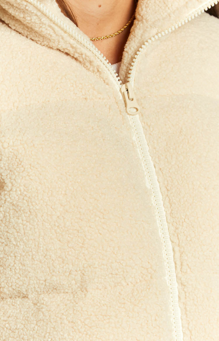 Front view of a cream teddy puffer jacket with a high collar and white front zipper