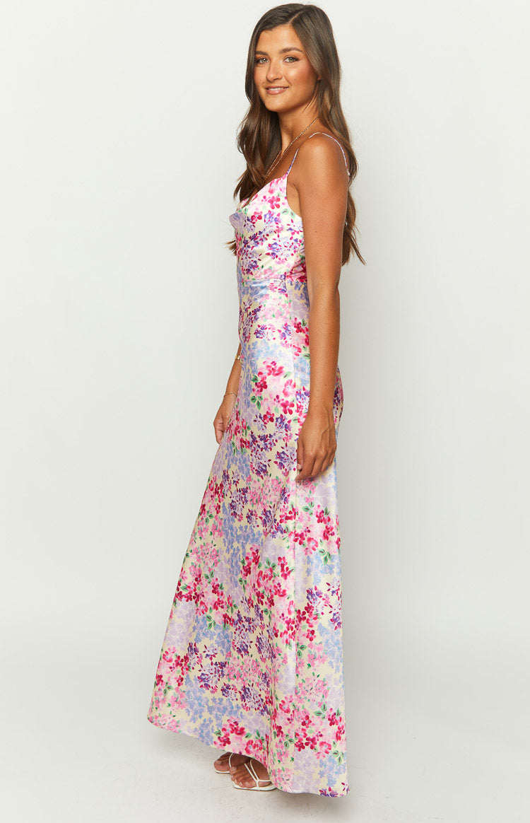 Side view of the yellow floral print maxi dress with a cowl neck, thin straps, and a long flowing skirt