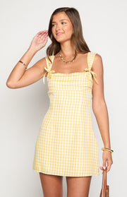 Front view of a yellow gingham mini dress with a square neckline, tie-up shoulder straps, and gathered bodice detail