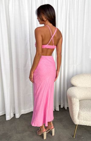 Back view of the pink maxi dress showing criss-cross straps, shirred back, and waist cutout