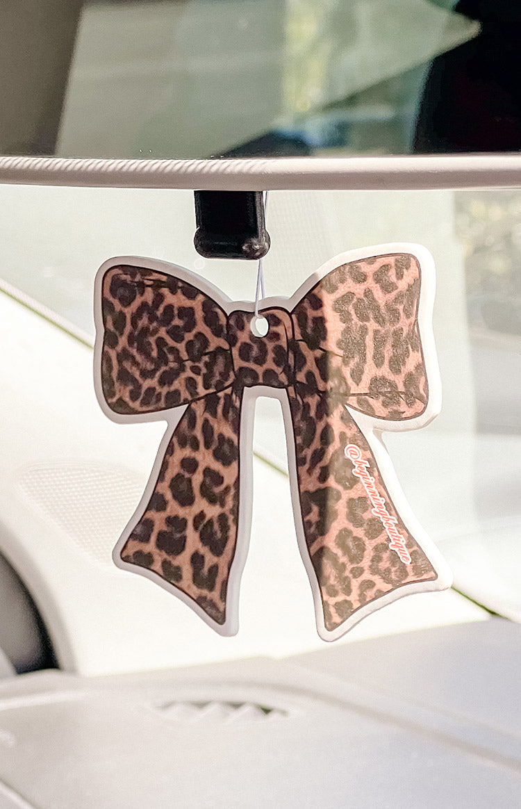 Leopard print bow air freshener with 'Beginning Boutique' text, in car
