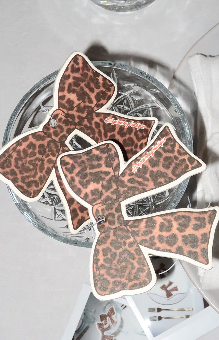 Several bow-shaped air fresheners in leopard print, featuring light pink and dark brown spots, arranged together