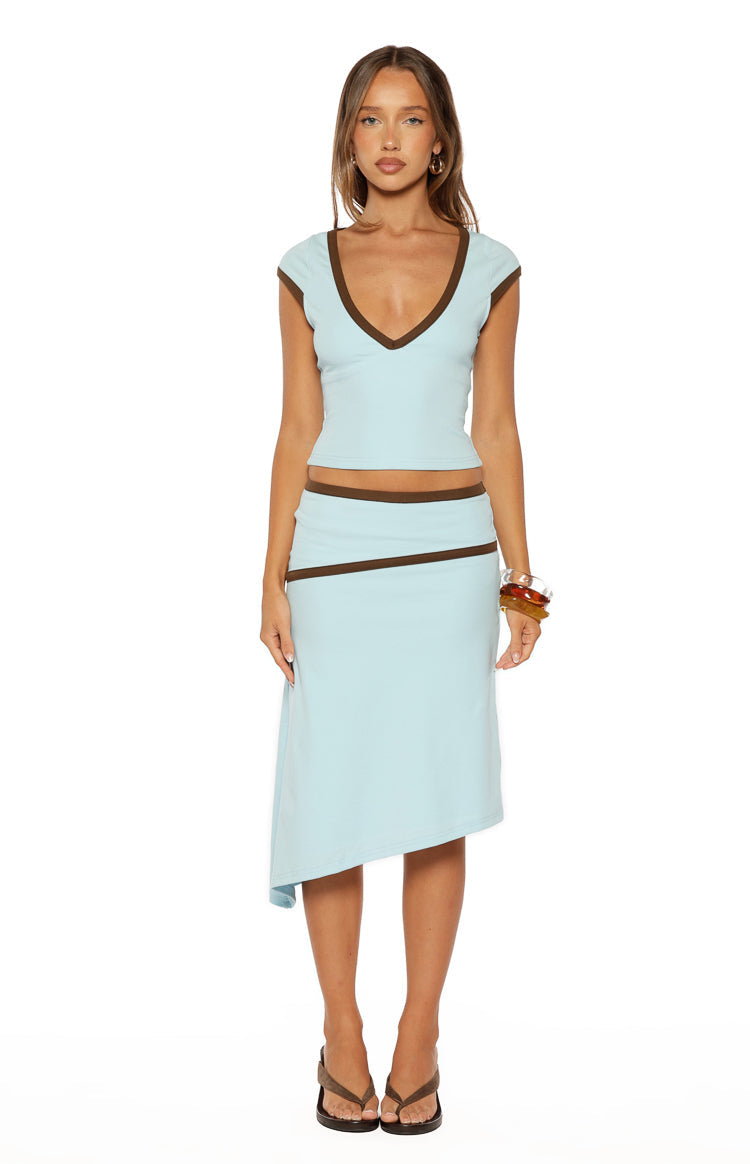 Front view of a light blue fitted jersey top with a deep V-neck and cap sleeves, featuring brown contrast binding