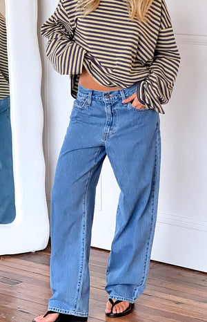 model wearing mid wash baggy jeans with black heels and a long sleeve top