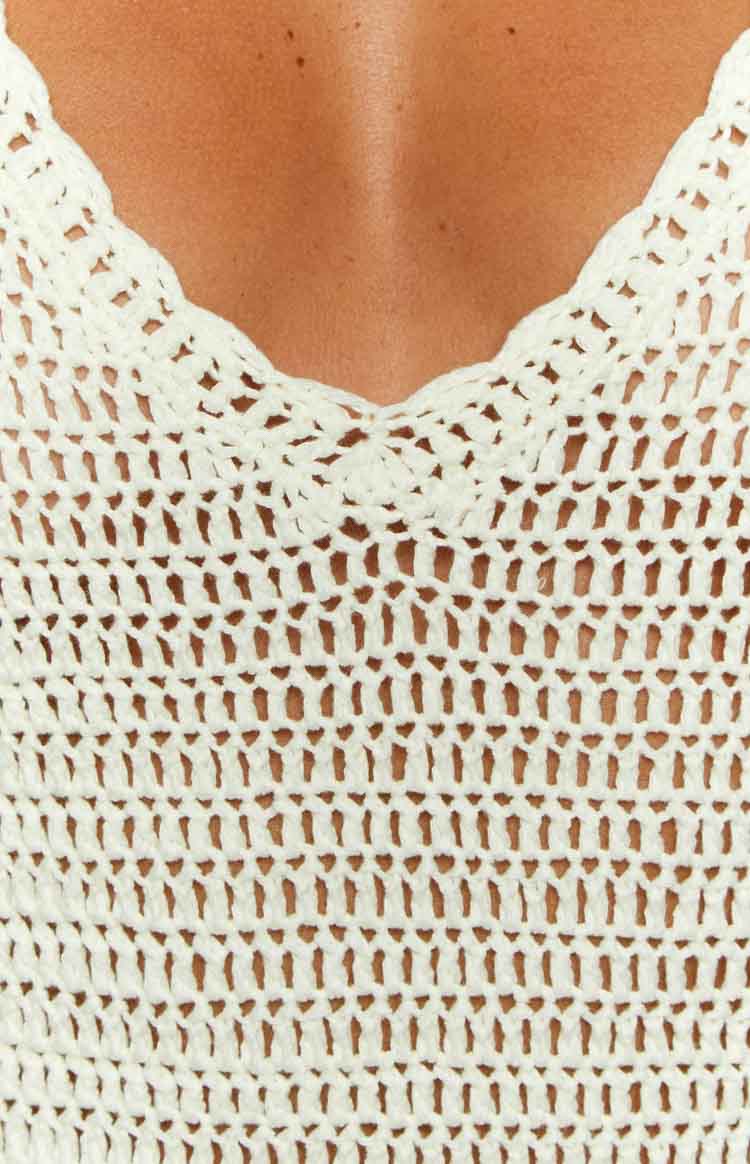 Close-up of the white crochet mini dress showing the scalloped V-neckline and open knit fabric