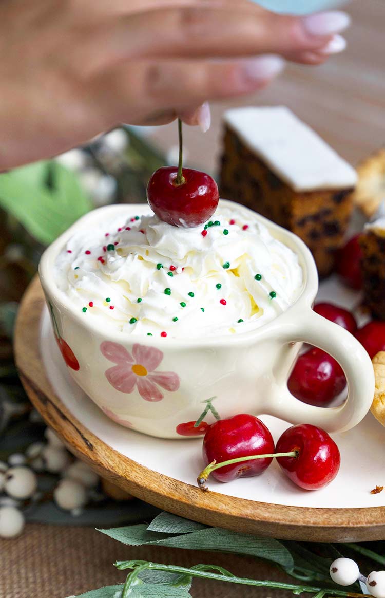 Side and interior view of a cream ceramic mug with red cherry and pink floral patterns