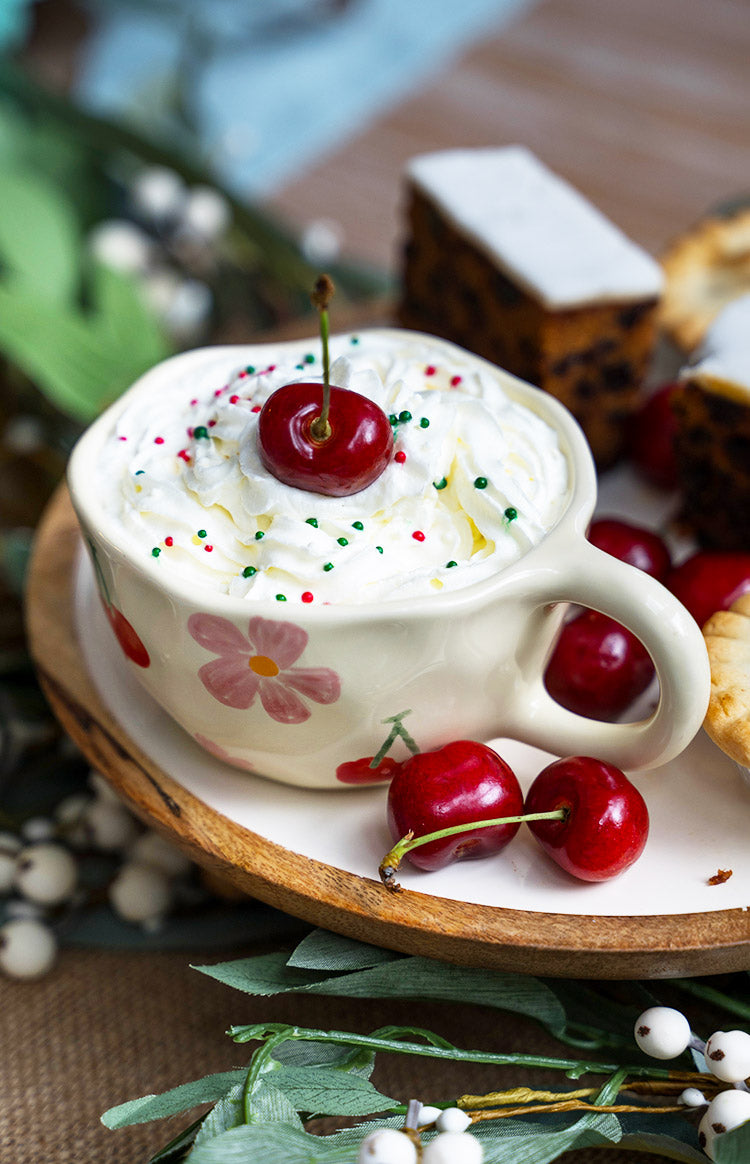 Top-down view of a cream mug with pink floral patterns and a red cherry design on the inside rim