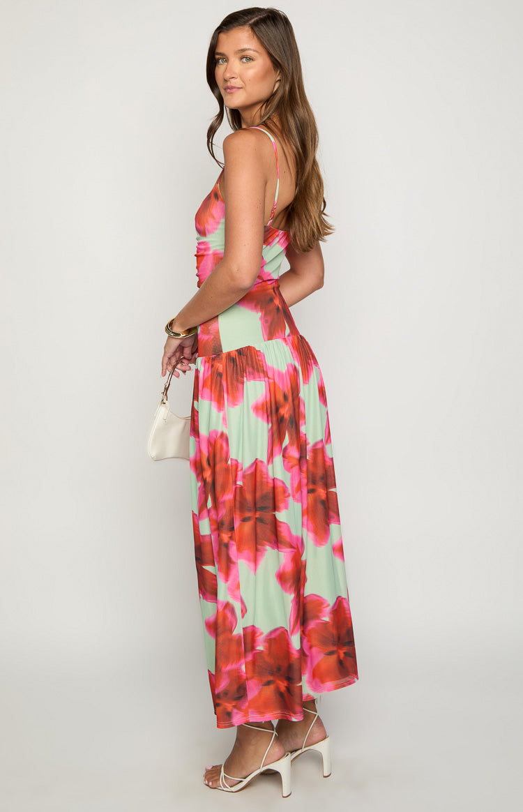 Side view of a green maxi dress with large pink and red floral print, showing the ruched bodice and flowy skirt