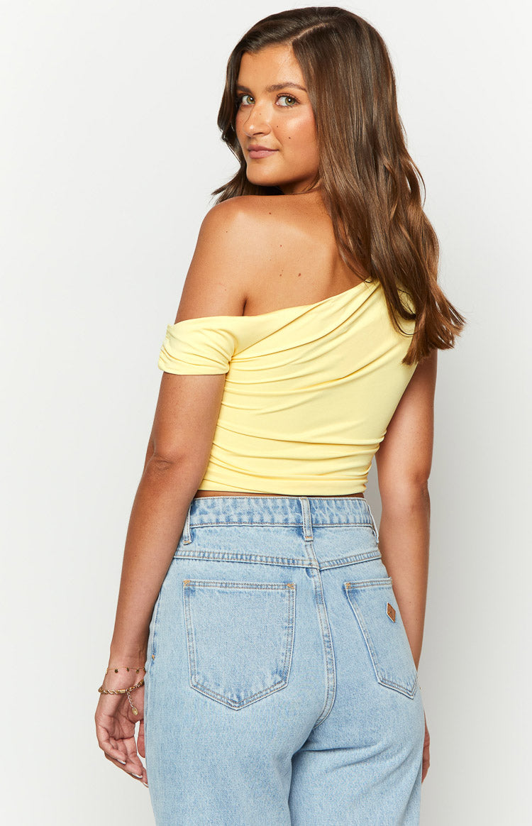 Close-up of the yellow off-shoulder crop top with draped neckline and ruched side detail